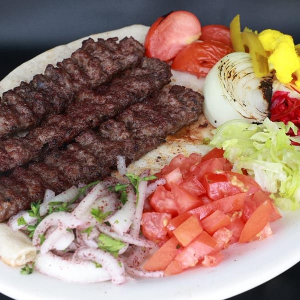 Erbil Kabob's grilled beef kabobs with roasted tomatoes, onions, pickled vegetables, and fresh salad.