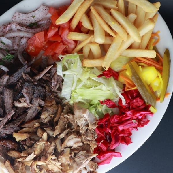 Erbil Kabob's shawarma plate with beef, chicken, fries, onions, tomatoes, lettuce, and pickled vegetables.